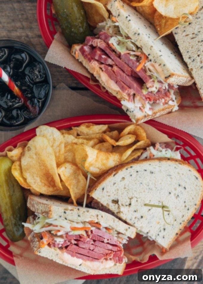 Two classic corned beef sandwiches with coleslaw and Russian dressing, served in baskets with potato chips and dill pickles, capturing a full deli experience