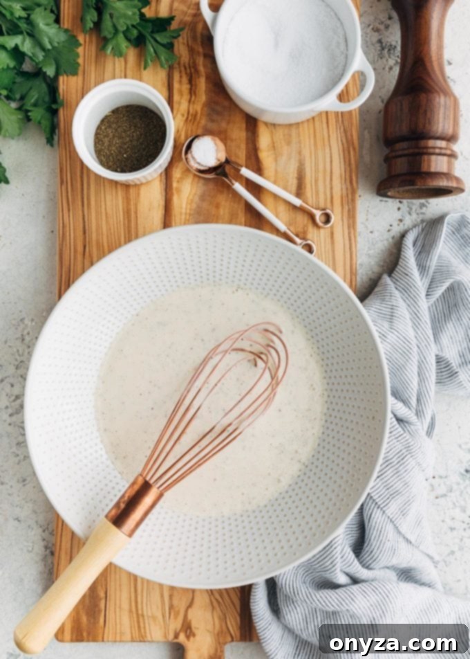 Creamy Homemade Deli Coleslaw 3 Ingredients for a creamy coleslaw dressing, including mayonnaise, apple cider vinegar, and celery seed, ready to be whisked in a bowl.