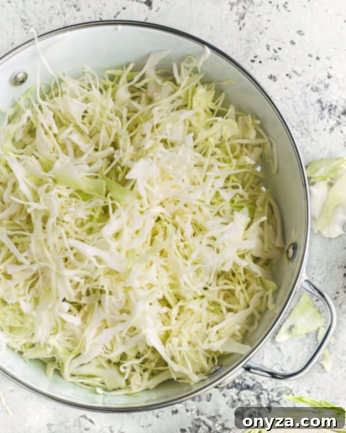 Creamy Homemade Deli Coleslaw 4 Freshly shredded green cabbage in a colander, illustrating the first step in preparing a crisp homemade coleslaw.
