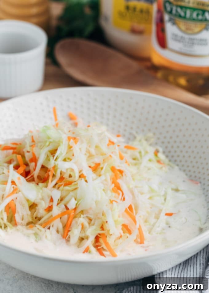 Creamy Homemade Deli Coleslaw 5 Shredded cabbage and carrots lightly coated in creamy coleslaw dressing in a mixing bowl.