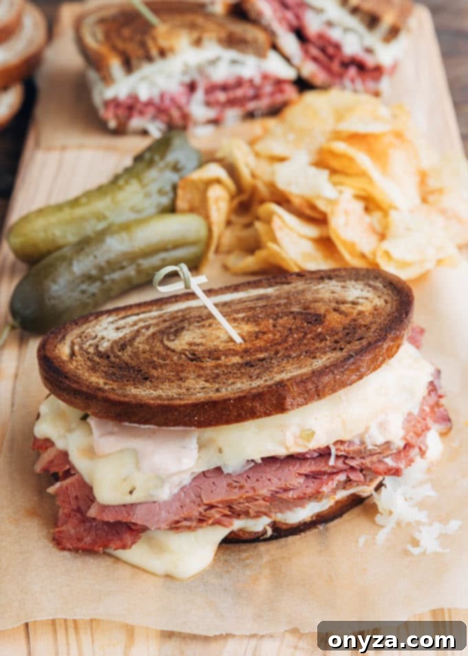 Homemade Reuben Sandwich Perfection 5 A delicious Reuben sandwich served on a wooden board, accompanied by a generous pile of potato chips and crunchy dill pickles
