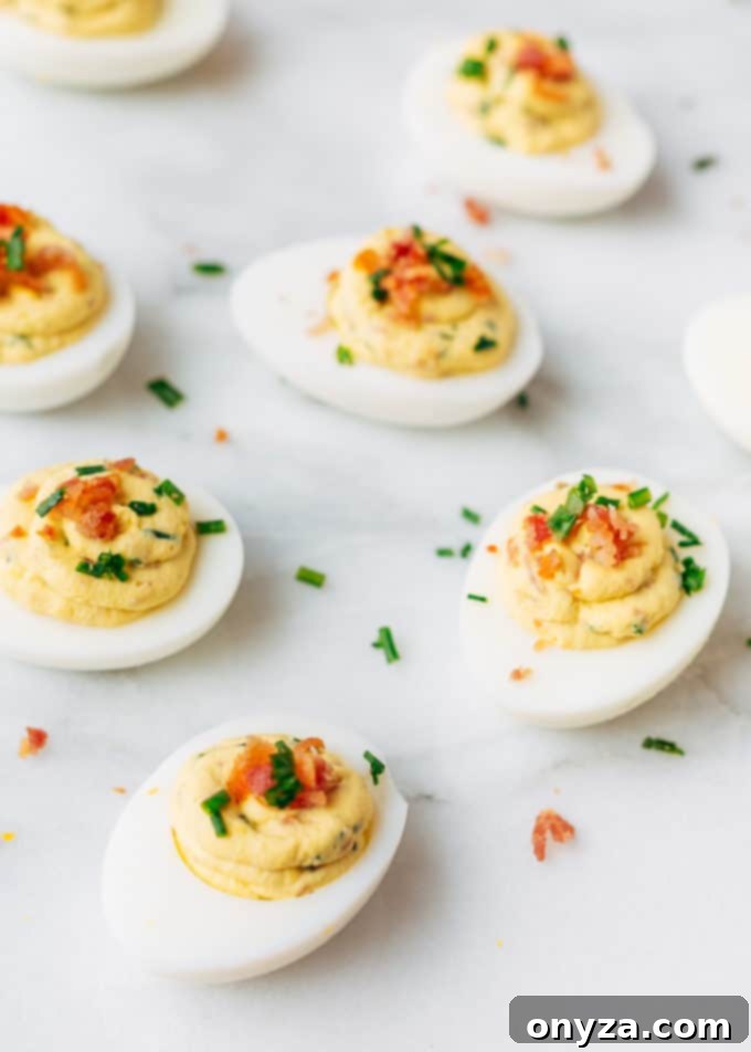 Zesty Horseradish Bacon Deviled Eggs 5 filled deviled eggs with bacon and horseradish on a white marble board