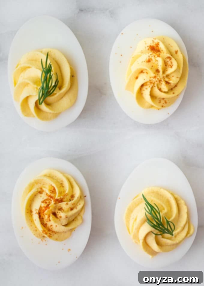 four deviled eggs with dill sprigs and paprika