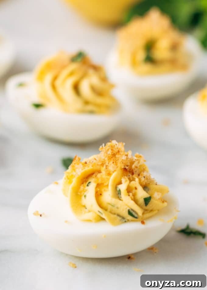 Rustic Italian Deviled Eggs with Garlic and Basil 2 Exquisite Italian Deviled Eggs on a white marble serving board, garnished with fresh basil and a crunchy Panko topping