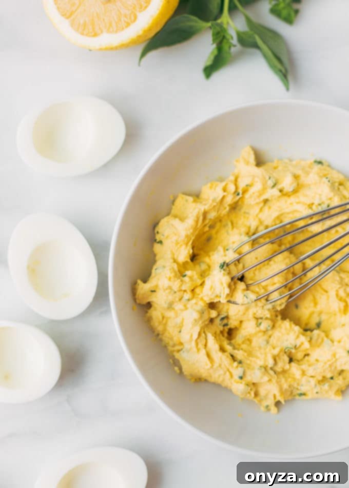 Rustic Italian Deviled Eggs with Garlic and Basil 4 Smooth Italian deviled egg filling in a mixing bowl with a whisk, ready for piping