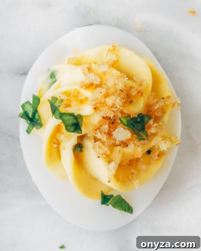 Rustic Italian Deviled Eggs with Garlic and Basil 5 Closeup of a single Italian deviled egg garnished with golden Panko breadcrumbs, fresh basil leaf, and Parmesan shavings