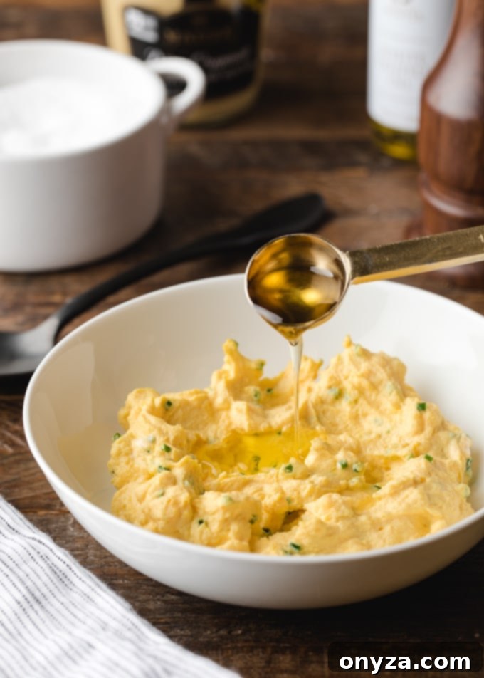 A teaspoon drizzling golden truffle oil into a bowl of creamy deviled egg filling, enhancing its flavor profile.