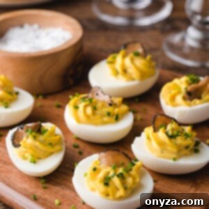 truffled deviled eggs with chives on a wood board