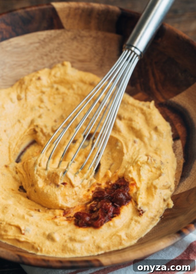 filling for chipotle deviled eggs in a wooden bowl with a whisk