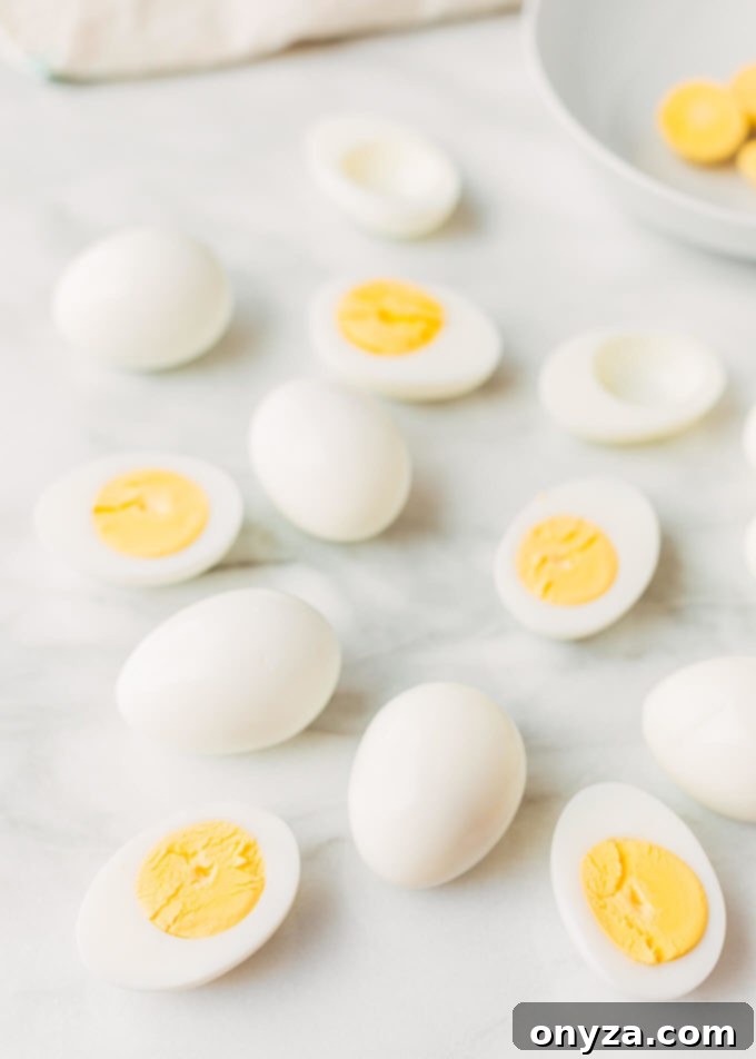 Whole and halved hard-boiled eggs artfully arranged on a sleek white marble board