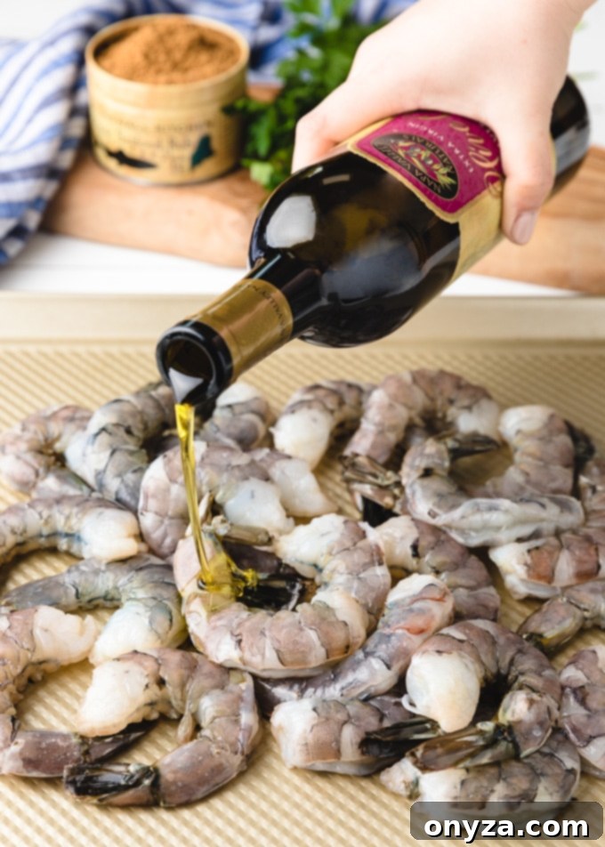 Signature Roasted Shrimp with Duo Dips 4 A bottle of Napa Valley Naturals by Stonewall Kitchen extra virgin olive oil gently drizzles over raw, shelled shrimp, ready for seasoning and roasting.