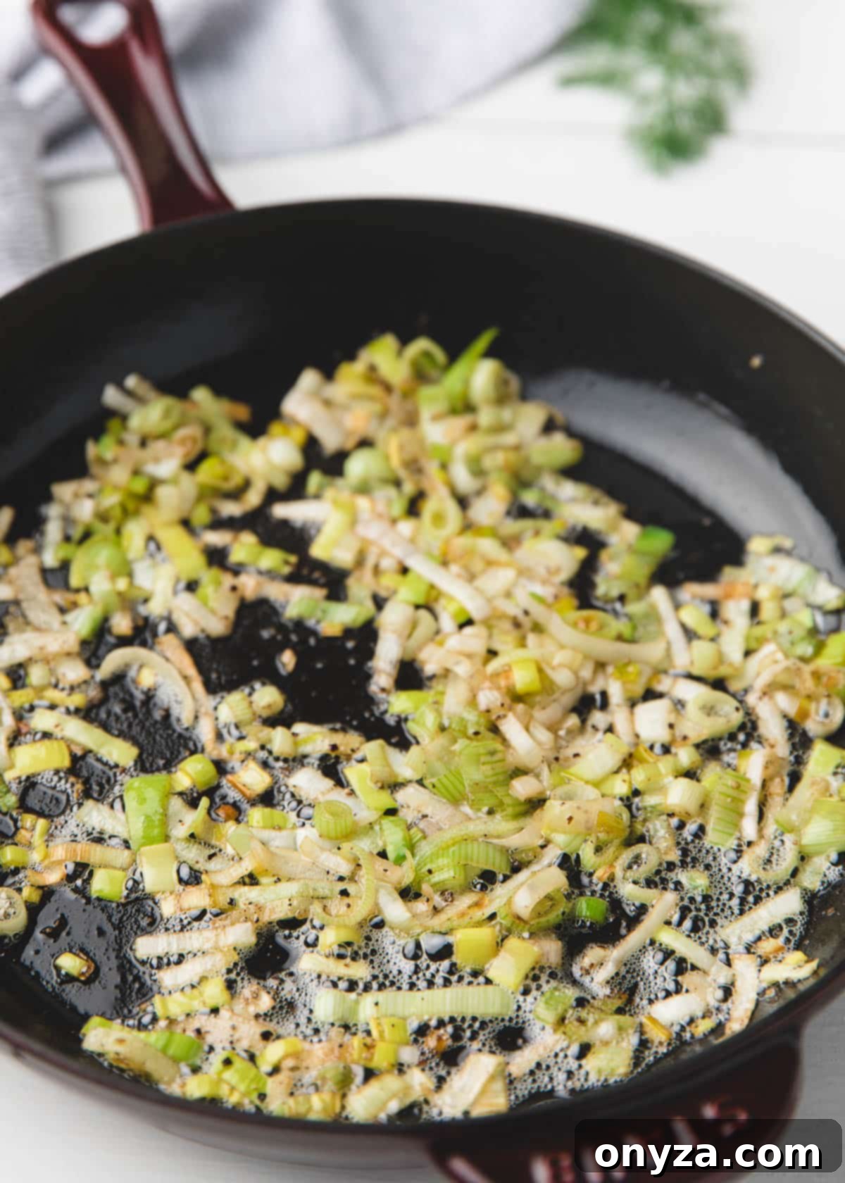 butter sauteed leeks in an enameled cast iron frying pan