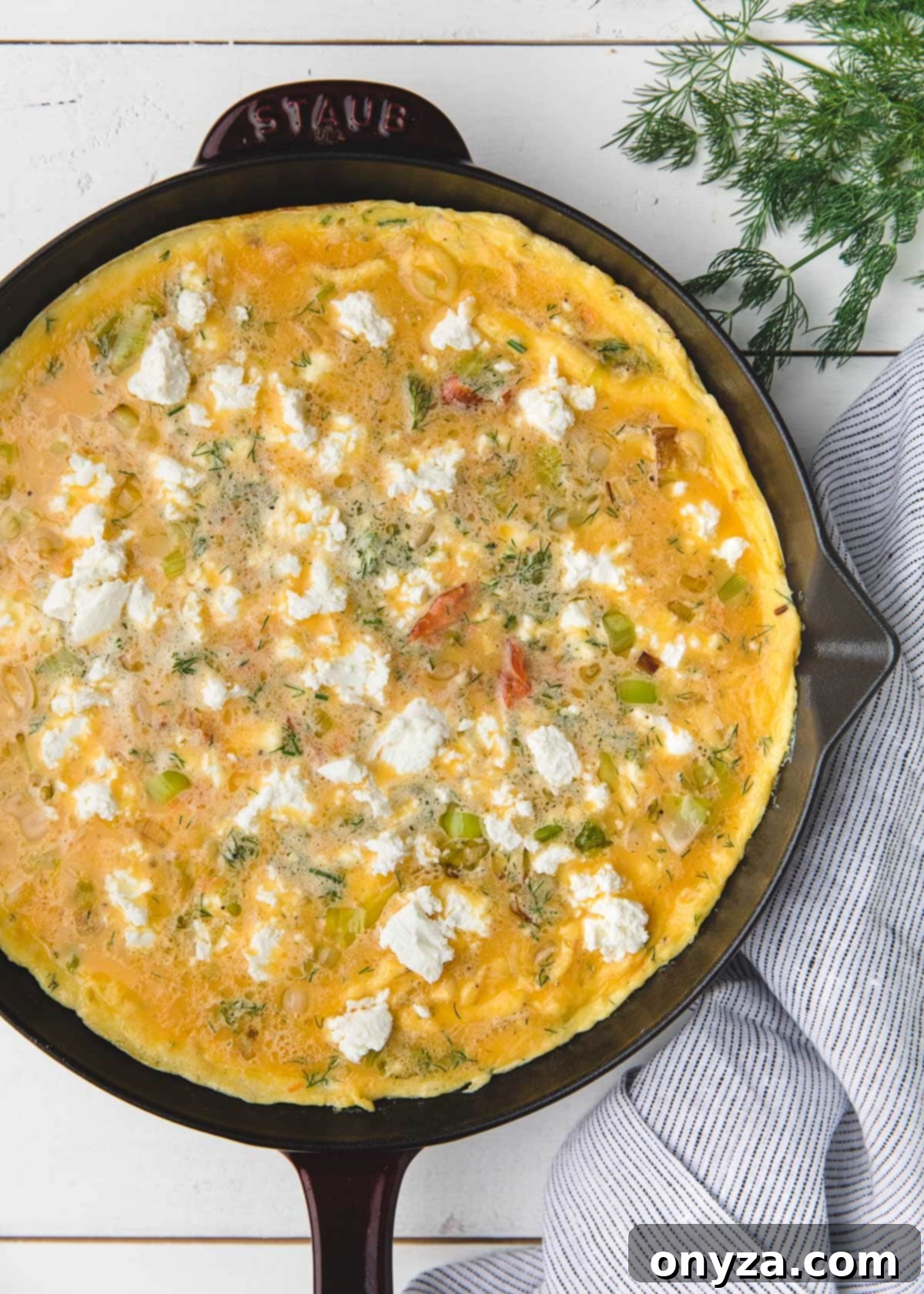 overhead photo of an unbaked smoked salmon frittata in a staub frying pan