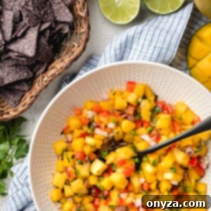 Fresh mango salsa in a bowl next to a basket of crispy blue corn chips.