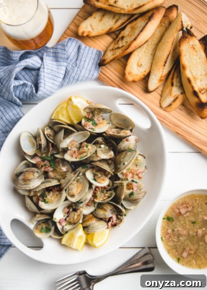 beer steamed littleneck clams in a white serving dish with a board of grilled bread slices