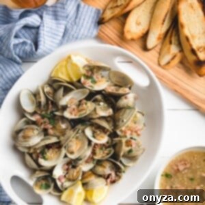 beer steamed littleneck clams in a white serving dish with a board of grilled bread slices