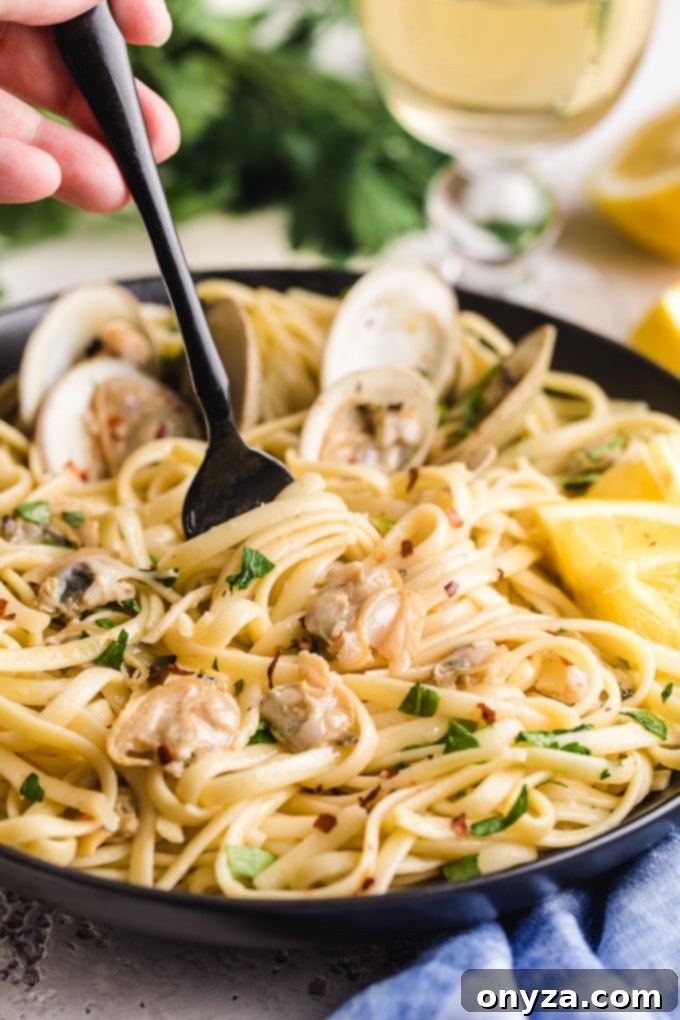 A bowl of freshly prepared linguine with clams, with a fork twirling pasta, ready to be enjoyed.
