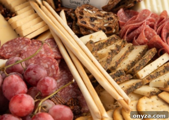 15 Perfect Crackers for Your Cheese Board 4 Grissini breadsticks elegantly arranged on a rustic cheese and charcuterie board, alongside various cheeses, meats, and olives.