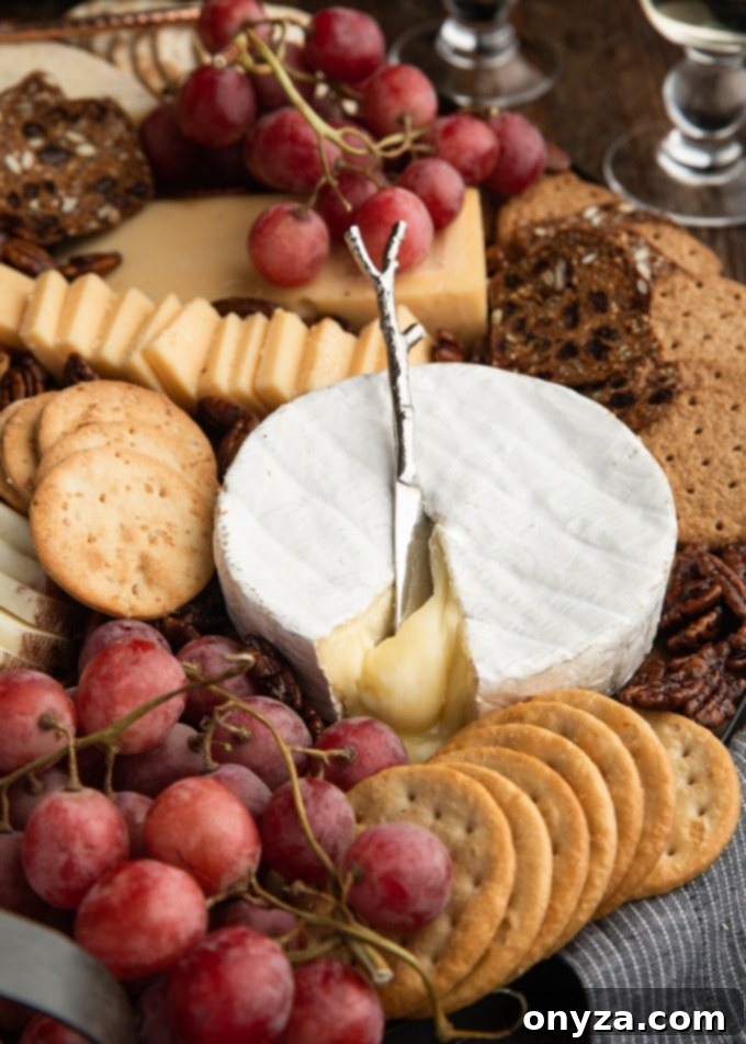15 Perfect Crackers for Your Cheese Board 6 A vibrant cheese board featuring an assortment of cheeses, grapes, and various crackers on a rustic wooden board, ready for entertaining.