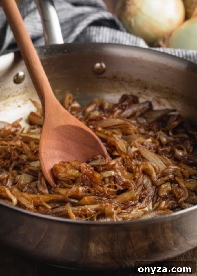 Mükemmel Karamelize Soğan Yapımı 2 Perfectly caramelized onions resting in a stainless steel skillet, accompanied by a wooden spoon, ready to enhance any dish.