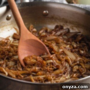 Mükemmel Karamelize Soğan Yapımı 8 caramelized onions in a stainless steel skillet with a wooden spoon