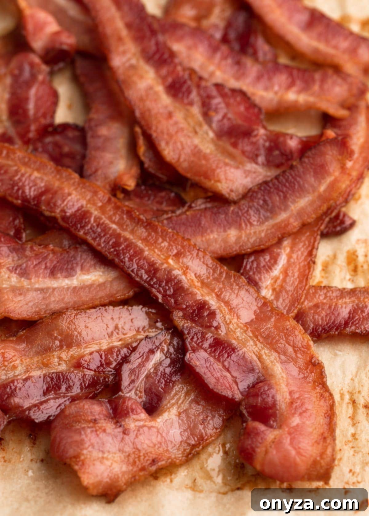 A generous pile of freshly baked bacon strips resting on a parchment-lined baking sheet, ready to be enjoyed.