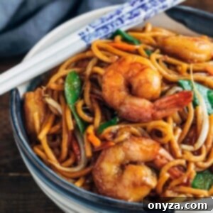 shrimp lo mein in a ceramic bowl with white chopsticks