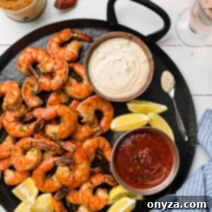 roasted shrimp cocktail with two dipping sauces on a black handled platter
