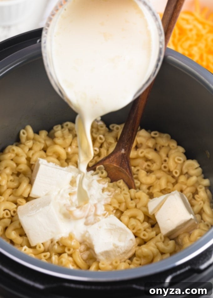 Instant Pot Mac and Cheese Four Irresistible Styles 6 pouring heavy cream into macaroni and cheese in the Instant Pot