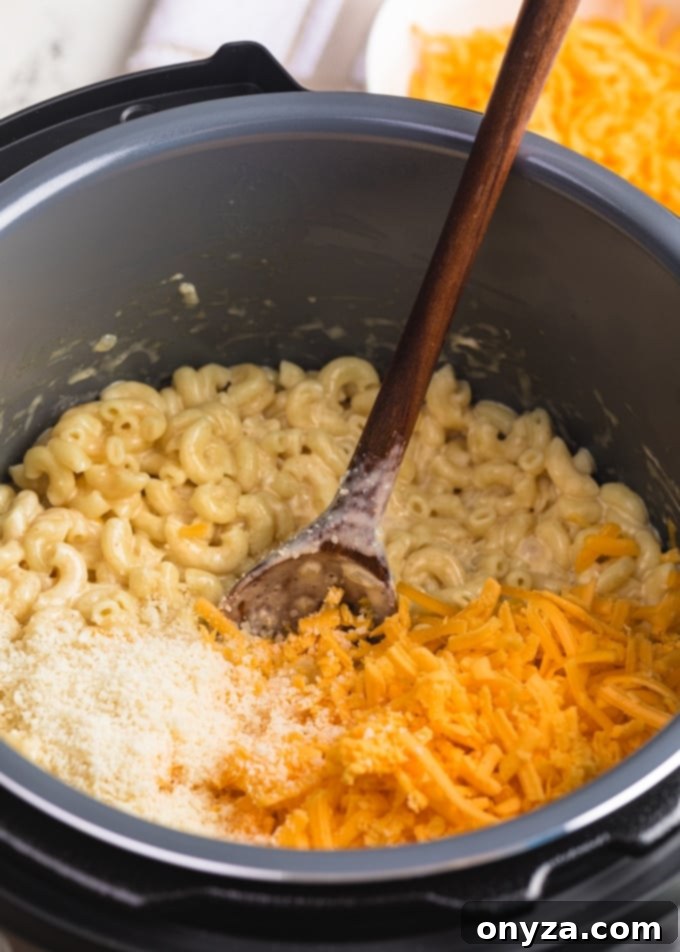 Instant Pot Mac and Cheese Four Irresistible Styles 7 grated cheddar and parmesan cheese being stirred into elbow macaroni