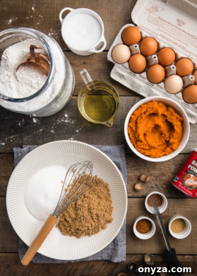 An overhead shot displays all the fresh and pantry staple ingredients neatly arranged, ready to be transformed into a delicious pumpkin bundt cake.
