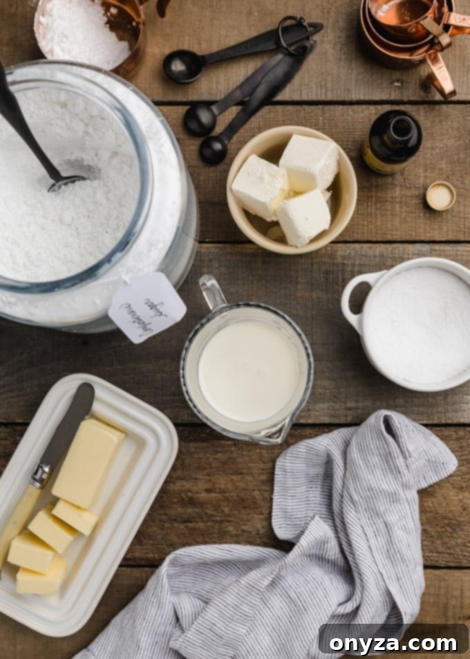 Velvety Cream Cheese Topping 3 Overhead view of essential ingredients for cream cheese glaze: softened cream cheese, butter, confectioner's sugar, milk, and a pinch of salt, arranged on a rustic wooden board.