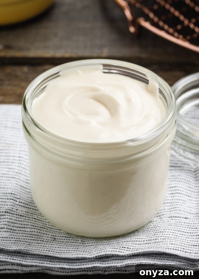 Velvety Cream Cheese Topping 6 Cream cheese glaze neatly stored in a glass Weck jar, placed on a blue and white folded napkin, suggesting its make-ahead convenience.