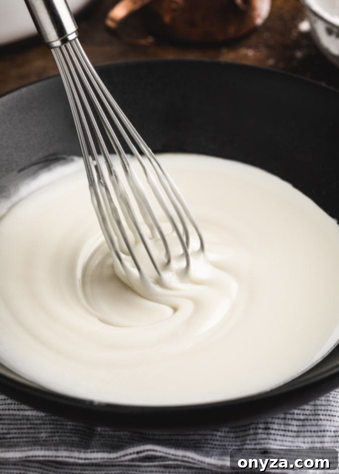 Simple Powdered Sugar Glaze 5 basic powdered sugar cake glaze in a black bowl with a whisk
