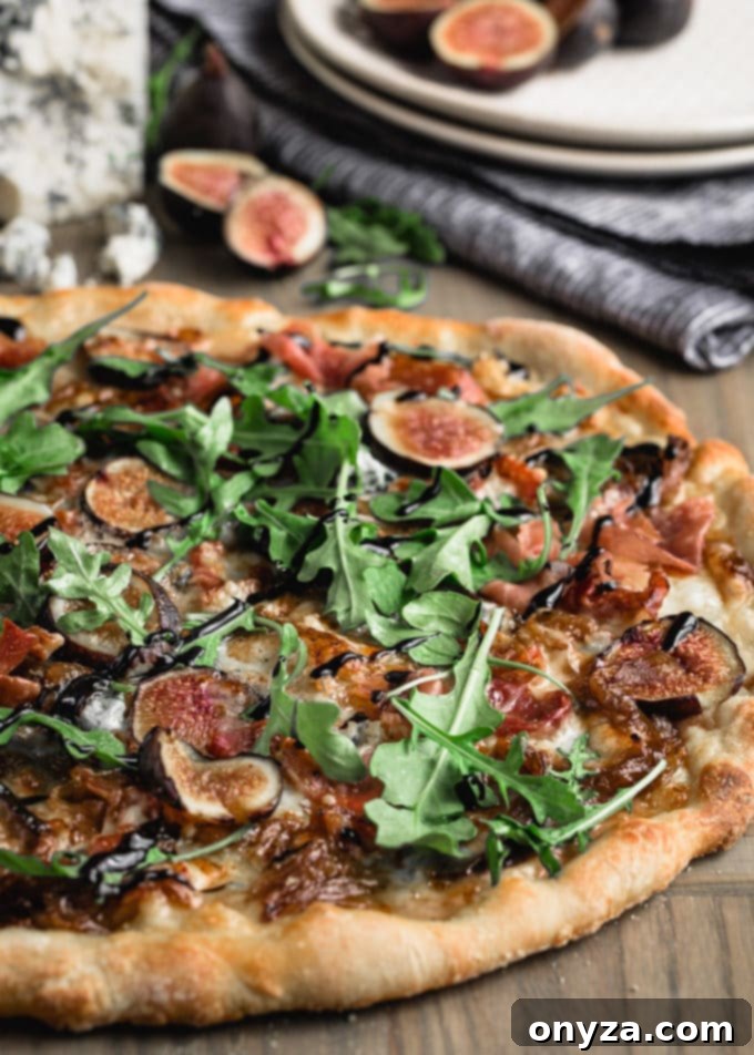 side view of a baked fresh fig pizza topped with baby arugula and a balsamic drizzle