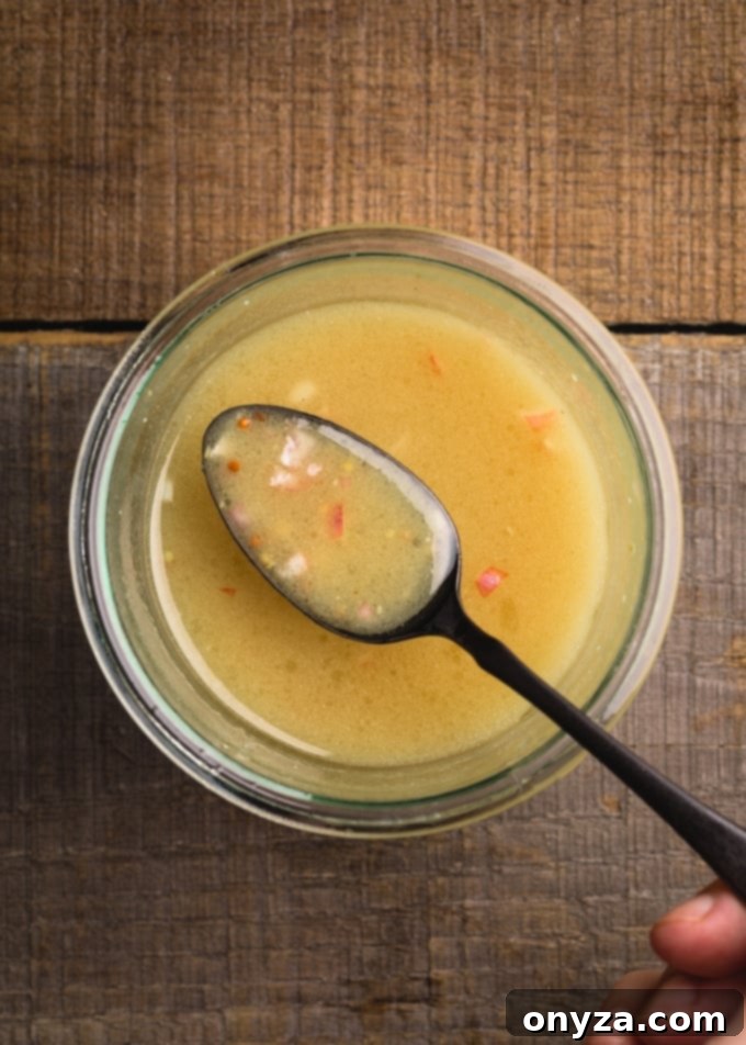 maple dijon vinaigrette on a black spoon over a glass jar