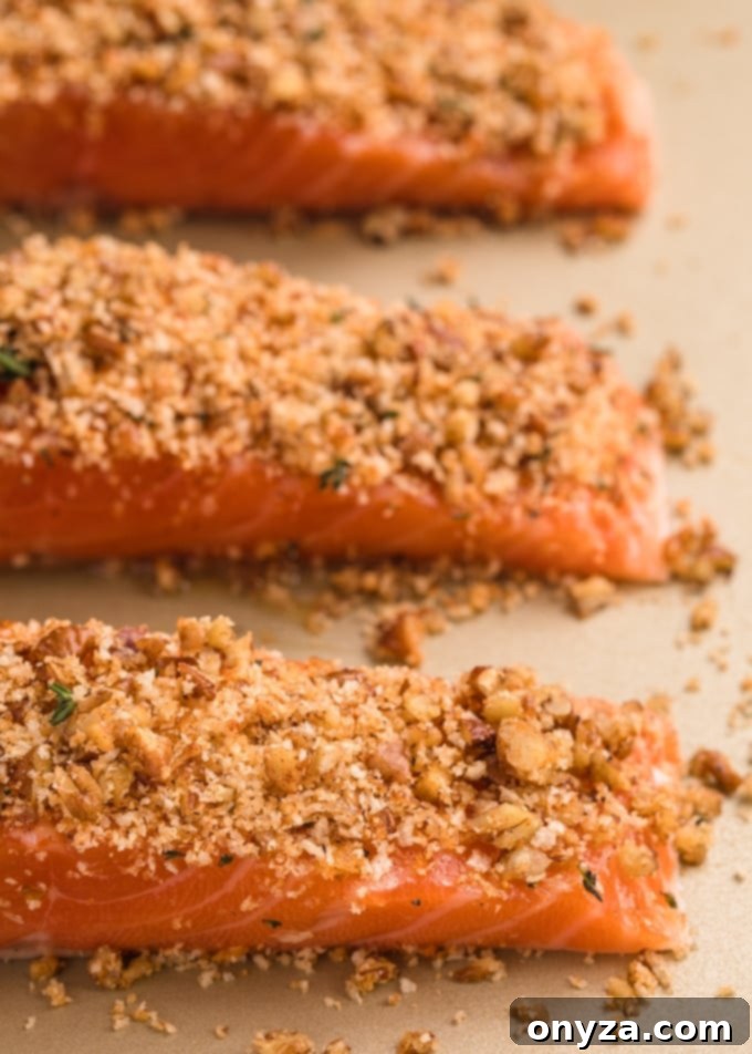raw salmon fillets on a baking sheet with pecan and panko crust