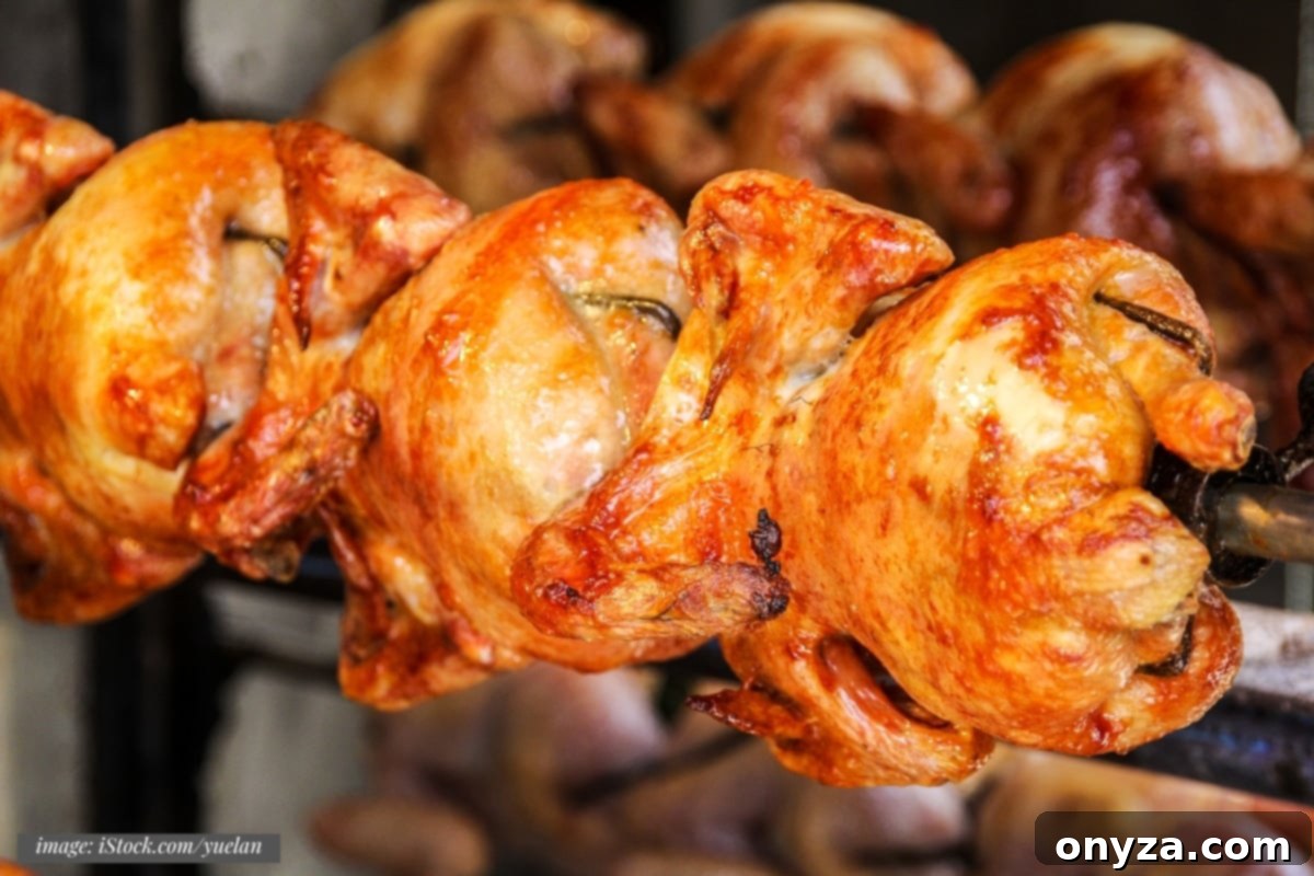 closeup of cooked chickens on a rotisserie spit