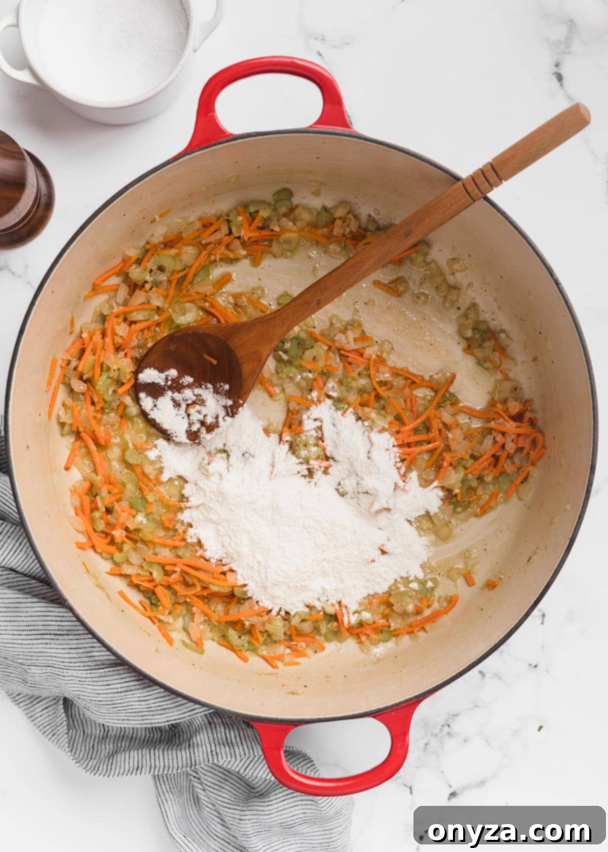 Hearty Chicken Gnocchi Comfort 7 all-purpose flour added to a Dutch oven of sauteed mirepoix with a wooden spoon