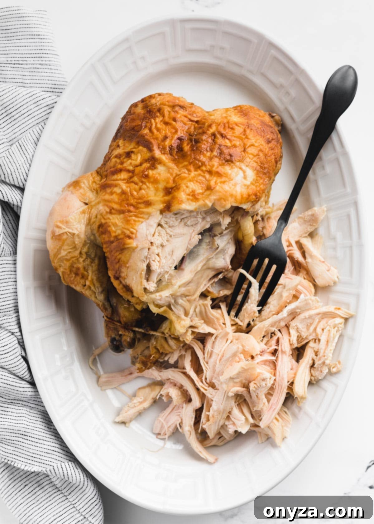 Hearty Chicken Gnocchi Comfort 10 partially shredded rotisserie chicken on a white platter with a black fork