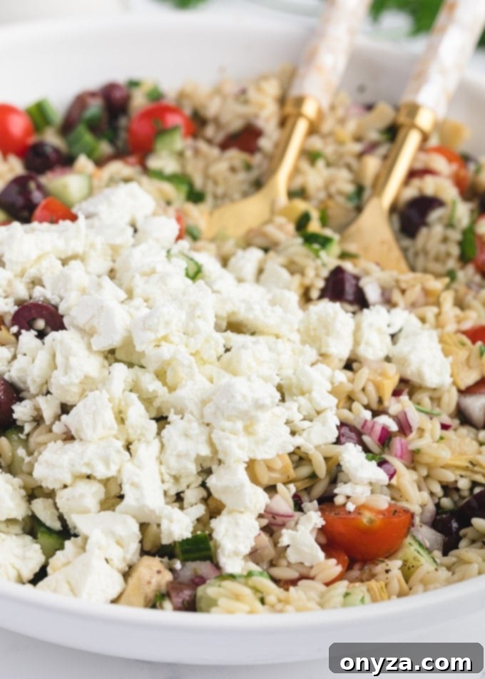 Zesty Feta Orzo Salad 7 Close-up of crumbled Greek Feta cheese nestled amongst orzo pasta, Kalamata olives, and fresh vegetables in a bowl of salad, highlighting its creamy texture.