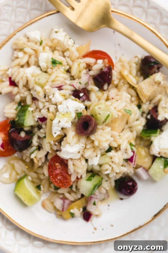 Zesty Feta Orzo Salad 9 Close-up, overhead shot of Orzo Salad with Feta cheese, Kalamata olives, and chopped parsley on a white and gold plate, showcasing the vibrant ingredients.