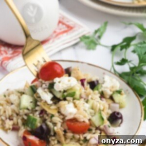 Zesty Feta Orzo Salad 10 Orzo Salad with Feta on a white and gold plate, being scooped up with a gold fork
