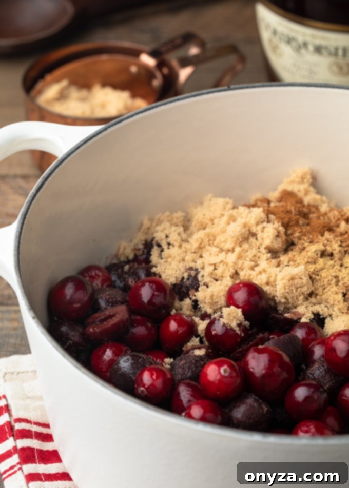 cranberries and frozen cherries in a white pot with brown sugar and cinnamon