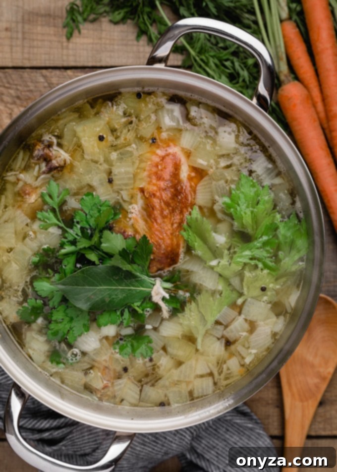 An overhead view of rich turkey stock gently simmering in a large pot, with a bouquet garni of herbs visible.