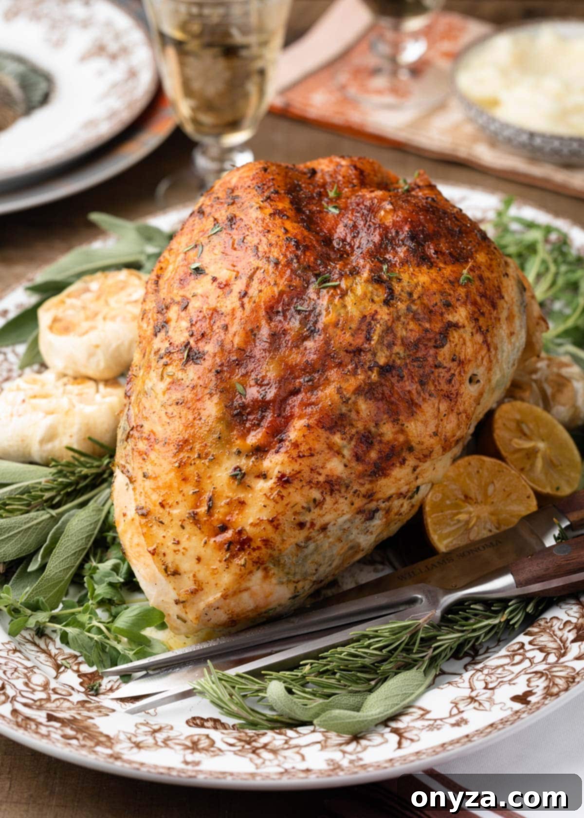 Beautifully roasted herb turkey breast on a serving platter, garnished with fresh herbs and roasted garlic