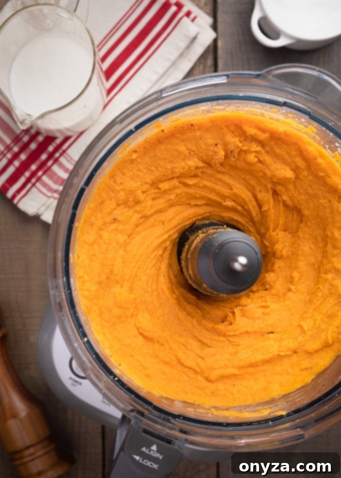 Velvety Brown Butter Sweet Potatoes 7 Smooth, whipped sweet potatoes swirling inside a food processor bowl, ready for serving.