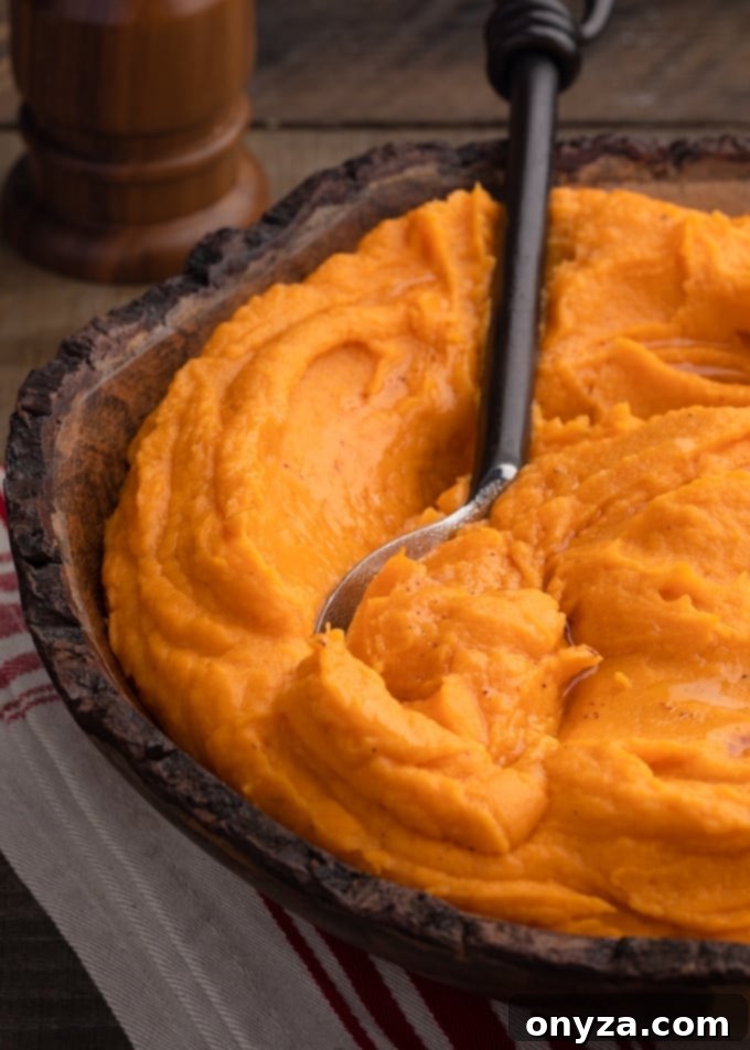 Velvety Brown Butter Sweet Potatoes 8 A wooden bowl filled with luscious brown butter whipped sweet potatoes, with a serving spoon resting beside it, ready to be enjoyed.