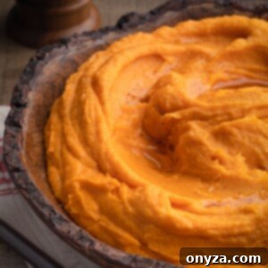 Velvety Brown Butter Sweet Potatoes 9 A beautiful wooden serving bowl filled with creamy brown butter whipped sweet potatoes, ready to be enjoyed.