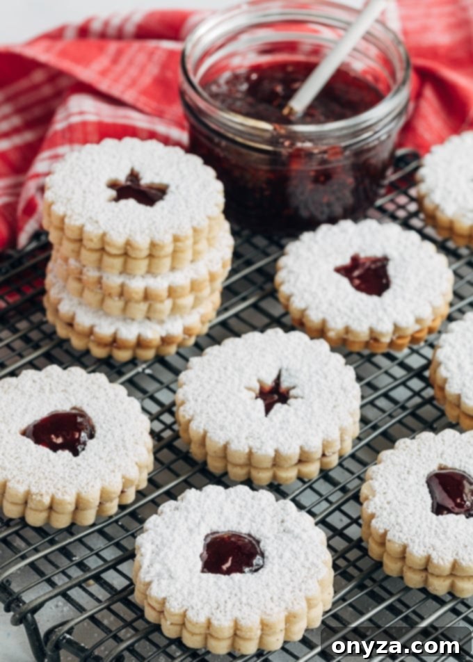 Linzer cookies with raspberry jam on a cooling rack, showcasing their elegant design and festive appeal.